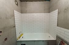 Укладка настенной плитки-кабанчик над ванной с заводом на раковину